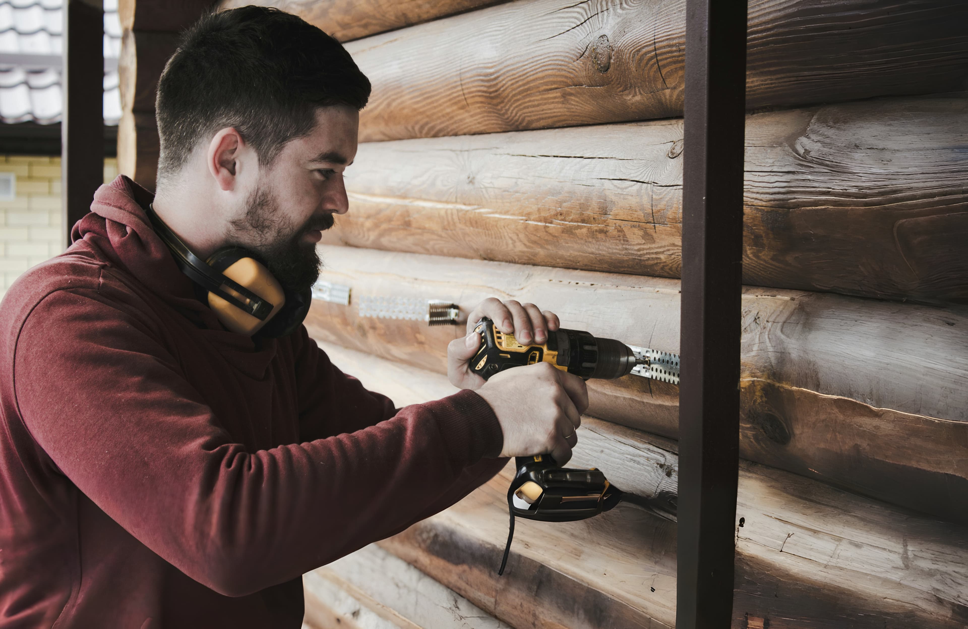 Contractor drilling into a timber wall